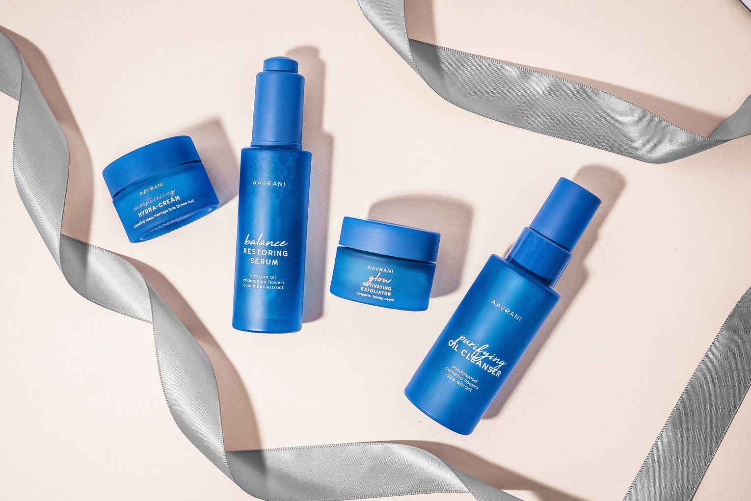 three blue skin care products on a white surface with a silver ribbon